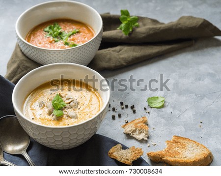 Homemade autumn soups -  pumpkin cream-soup and tomato cream soup on a linen towel on a gray background. Open space
