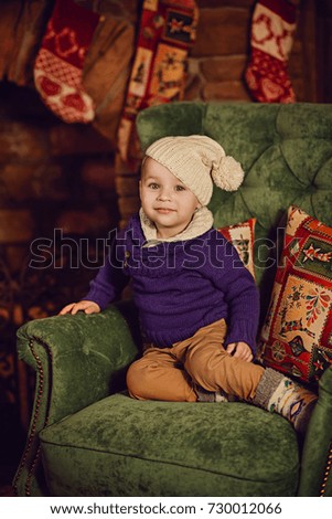 little boy sitting near a Christmas tree and a fireplace and waiting for a new yea