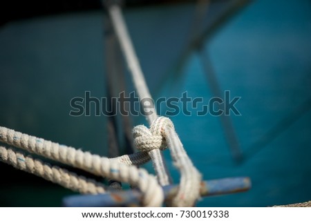 Yacht moored in marina.
Closeup picture of a rope tying the yacht to the pier.