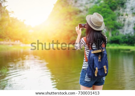 woman photographer take photo the lake and mountain by camera.Asian lady tourist walking on the bridge on vacation.
