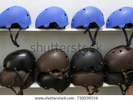 Blue, black and brown extreme sport helmets on the shelf with white background