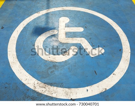 Close up white lines sign of disabled parking on blue painted concrete street.