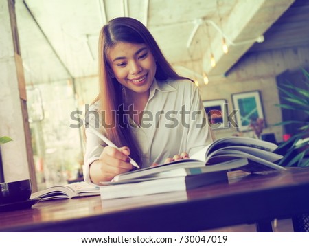 Beautiful Asian woman working reading a book in coffee shop.