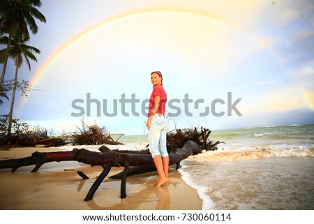 girl on sand beach under rainbow 