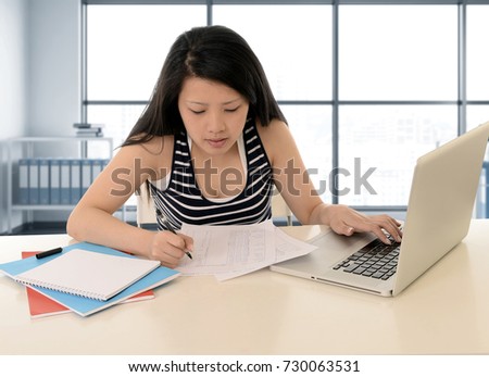 happy young asian american student woman working with a smile at modern library office and studying for exam with computer laptop in business and education success concept