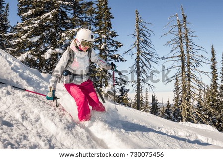 Woman skier rides through powder snow to the mountains. Winter sports freeride.