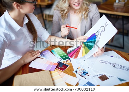 Two young fashion designers choosing trendy colors for new collection of clothes