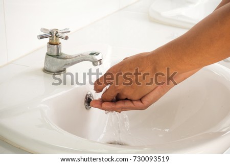 Asian woman hands washing under clean water pour. Dirty tap with white bowl in public rest room.