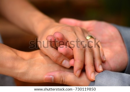 Both hands hands of a female and male married couple are holding onto one another 