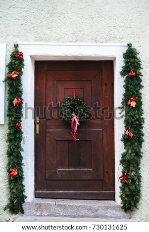 Christmas decoration of the door with a beautiful traditional wreath. Celebrating Christmas, decorating the house.