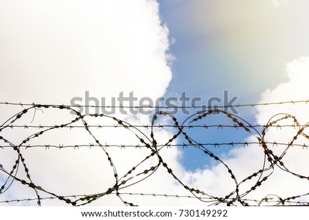 Barbed wire on the sky background and sun leak on the top right side.