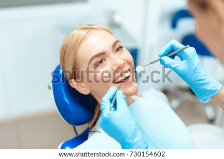 The woman came to see the dentist. She sits in the dental chair. The dentist bent over her. Happy patient and dentist concept. Royalty-Free Stock Photo #730154602