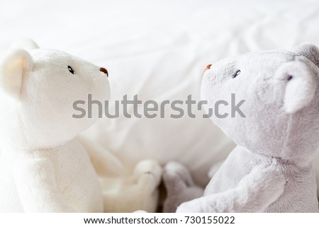 Two soft teddy bears side facing each other with white blanket background. Newborn baby concept. Nice image for nursery interior design.