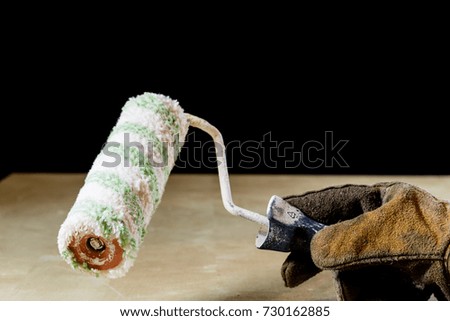 Hand in glove with tool for work in workshop. Hand protected by working coat. Workshop tool. Black background.