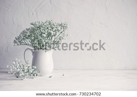Small white flowers on a white background. Soft home decor. Gypsophila flowers. White flowers in a vase. Retro style. Royalty-Free Stock Photo #730234702
