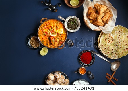 Indian cuisine on diwali holiday: tikka masala, samosa, patties and sweets with mint chutney and spices. Dark blue background, copy space. Diwali celebration dinner