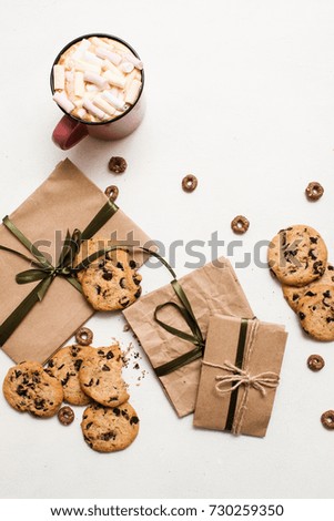 Preparing gifts with sweets and cup of latte. Small elegant presents on white table with homemade chocolate scones and delicious hot drink with marshmallow, top view picture