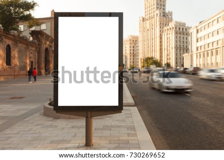 Blank vertical street billboard stand with city background. 