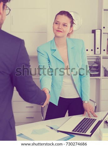 Female company manager meeting male client with handshake in workplace