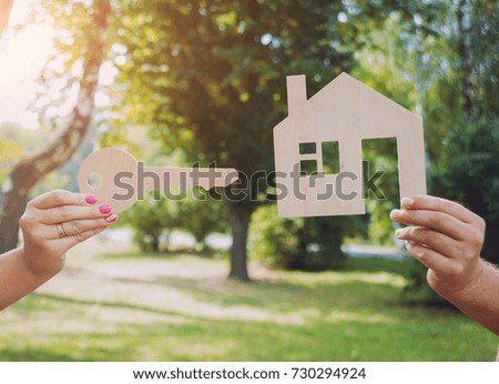 Young woman holding model of house at her hands. Outdoors. Summertime. Real estate and property concept