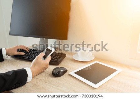 Businessman hand using smart phone and tablet working with computer in office