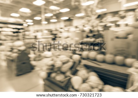 Blurred image Halloween decoration inside retail store in Houston, Texas, USA. Pile of pumpkins on hay, corns, garden cart wagon and scarecrow on display. Holiday festive background. Vintage tone