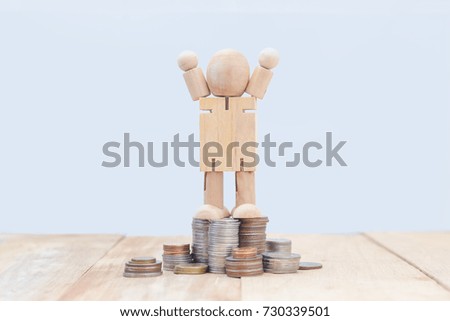 Wooden mannequin standing on stack of silver or gold coins