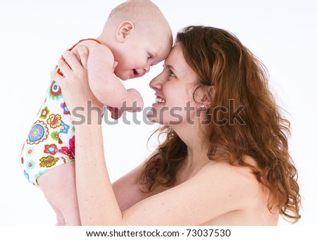 Mom is holding a little girl. They look at each other and smile.On a white background