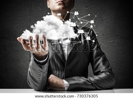 Businessman in suit keeping cloud with network connections in hand with gray wall on background.