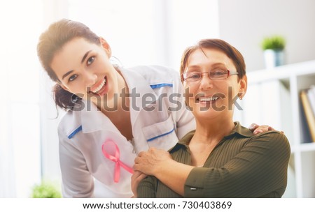 Pink ribbon for breast cancer awareness. Female patient listening to doctor in medical office. Raising knowledge on people living with tumor illness. Royalty-Free Stock Photo #730403869