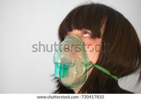 Close up image of a young woman with asthma using oxygen mask. White background, vertical, studio picture