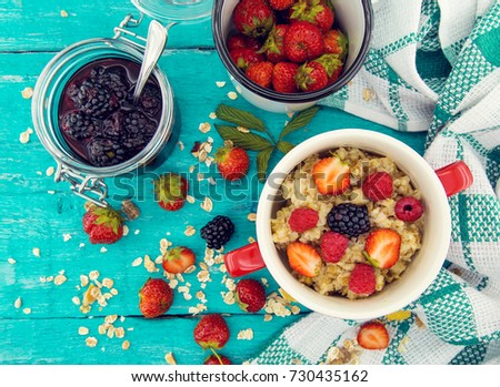 Organic cottage cheese with blackberry, strawberry and raspberry in a white ceramic bowl on the kitchen table. Dairy products for the breakfast. Healthy food concept. Top view.