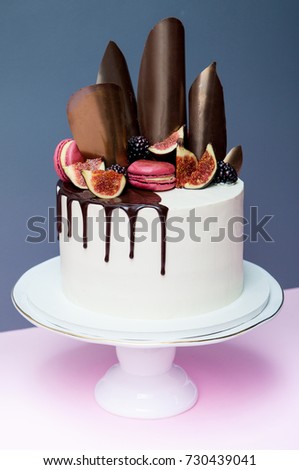 Cake decorated with chocolate waves, pink macaron and fresh figs
