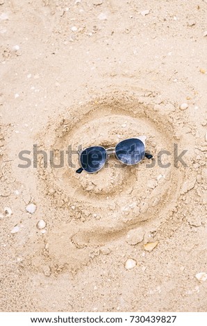 drawing on sand, drawn smile in the form of a spiral, in sunglasses
