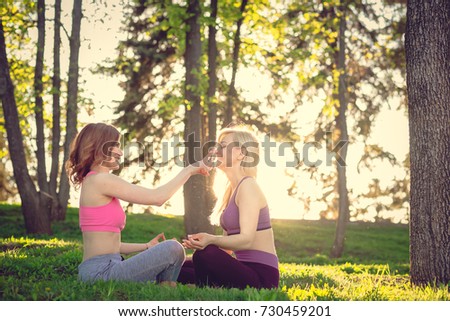 two Young woman doing yoga in morning park