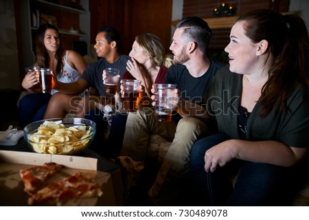 group of friends watching tv at night drinking beer