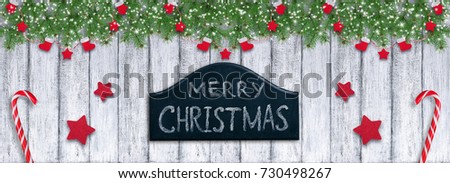 Christmas background in vintage style with Santa boot and mitten hanging on spruce branches, signboard and New Year lollipops on wooden planks in Shabby Chic style.