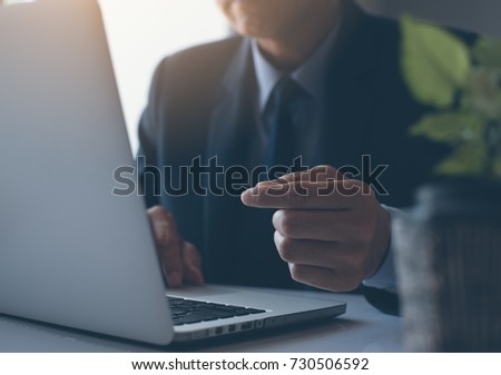 Businessman in black suit working on laptop computer in office, close up