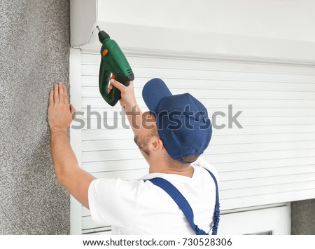 Man installing roller shutter on window Royalty-Free Stock Photo #730528306
