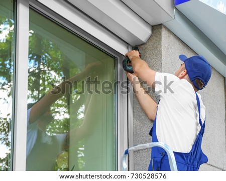 Man installing roller shutter on window Royalty-Free Stock Photo #730528576
