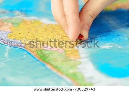travel and tourism concept, vacation. A man pins a pin to the world map. Traveling in South America. Close up