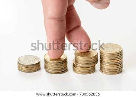 Fingers walking on the steps of metal money coins isolated above white background.