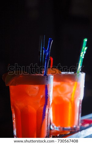 A beautiful red cocktails with slice of orange and cherry in a tall glasses. close-up