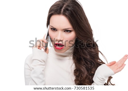 Young dissatisfied woman with bright makeup talking on smartphone, isolated on white