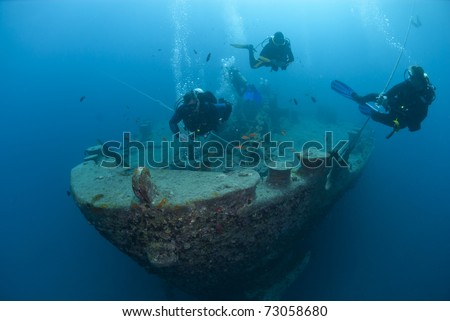 Silhouettes of scuba divers exploring the bow of the SS Thistlegorm shipwreck. SS Thistlegorm, Straights of Gubal, Red Sea, Egypt. Royalty-Free Stock Photo #73058680