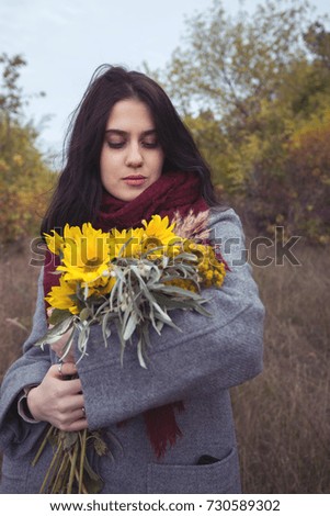 Portrait of romantic girl with sunflowers in the autumn forest. Toned image.