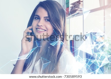 Cheerful young office employee is talking on her phone while standing near a bookcase. There are polygons in the foreground. Toned image double exposure