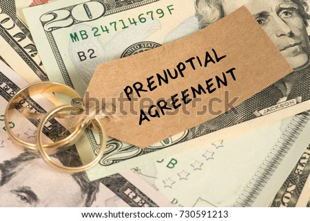 Dollar bills, wedding rings and a marriage contract Royalty-Free Stock Photo #730591213