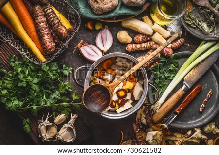 Pot with sliced colorful vegetables and cooking spoon on dark rustic table background with organic vegetarian ingredients and kitchen tools , top view. Healthy and clean food and eating  concept. Royalty-Free Stock Photo #730621582