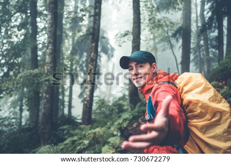 Toned photo of young man with backpack stretching hand